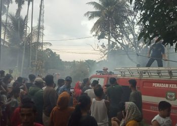 Kerumanan warga tengah menyaksikan upaya pemadaman api kebakaran oleh Damkar Siantar, Jumat (5/3) sore. (isiantar/jw-NM).