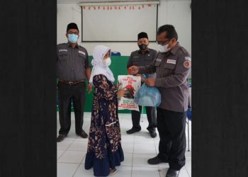 Pimpinan Bawaslu Kabupaten Simalungun tengah menyerahkan paket bantuan kepada salah seorang penerima, Senin (16/8/2021).