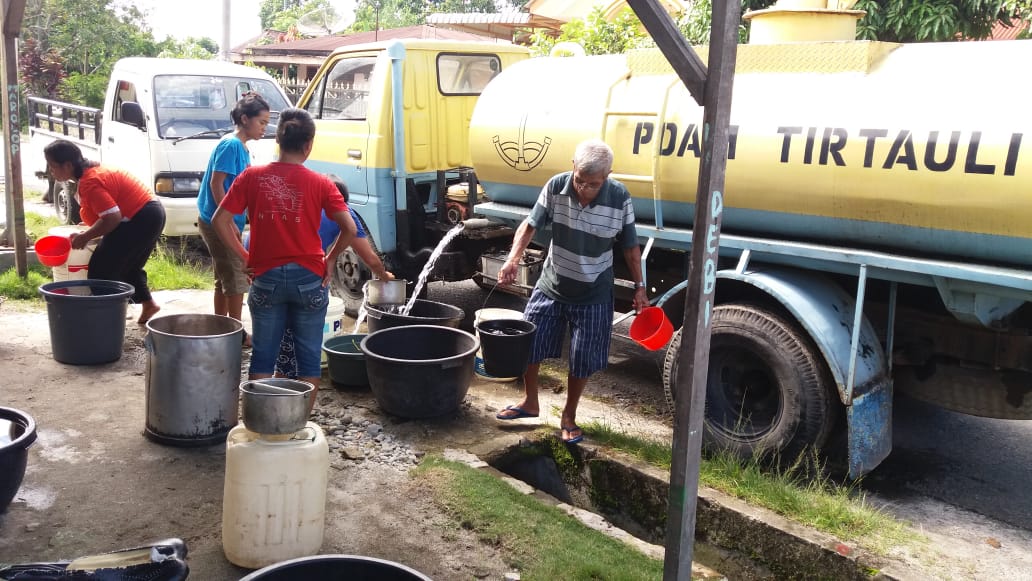 Mobil Tangki PDAM Tirtauli sedang mendistribusikan air bersih ke rumah-rumah warga.