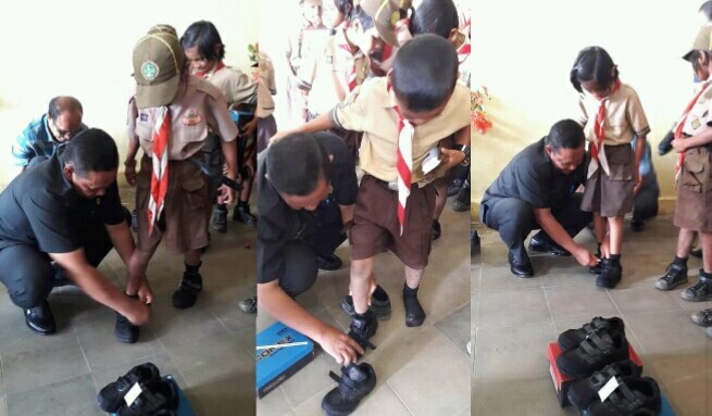Bupati Samosir, Rapidin Simbolon, memakaikan langsung sepatu bantuan ke siswa-siswi penerima, di SMP N 1 Ronggurnihuta, Sabtu (8/9).