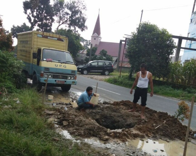 Tim teknis PDAM Tirtauli sedang memperbaiki pipa distribusi yang bocor di Jalan Siantar - Saribudolok, Senin (10/12).