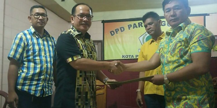 Ketua DPD Partai Golkar Mangatas Silalahi menyerahkan formulir pendaftaran bakal calon walikota kepada Asner Silalahi, Senin (11/11/2019). (isiantar/nda).