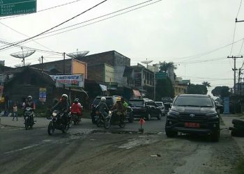 Untuk menghindari terjerembab ke lubang jalan, sebuah mobil plat merah tampak mengambil jalur dari beram jalan saat melintasi Jalan Pdt Justin Sihombing. (isiantar/nda).