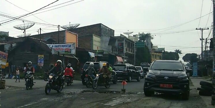 Untuk menghindari terjerembab ke lubang jalan, sebuah mobil plat merah tampak mengambil jalur dari beram jalan saat melintasi Jalan Pdt Justin Sihombing. (isiantar/nda).