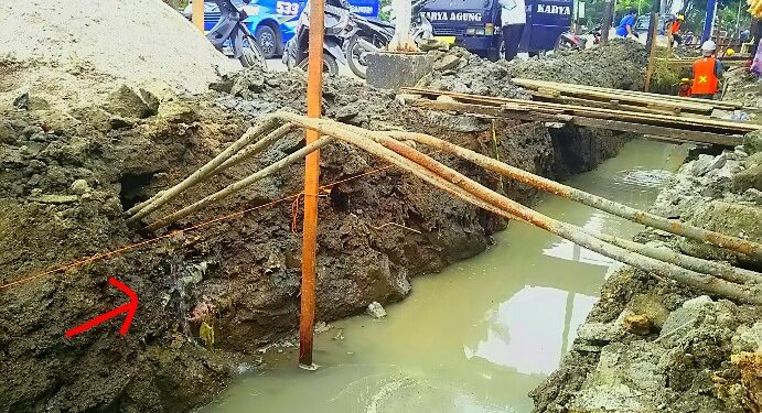 Air dari pipa yang bocor akibat penggalian proyek drainase mengalir dan menggenangi parit galian, Kamis (12/12). (isiantar/nda).