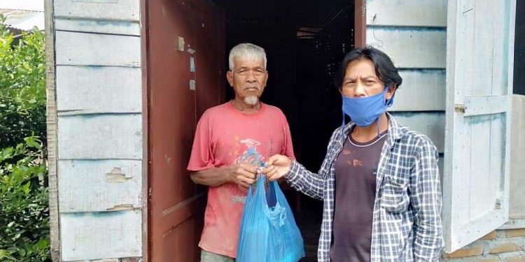 Salah seorang tim Relawan Cerdas Covid-19 Pematangsiantar saat menyerahkan langsung bantuan sembako ke rumah masyarakat yang berhak mendapatkan, Sabtu (23/5/2020).