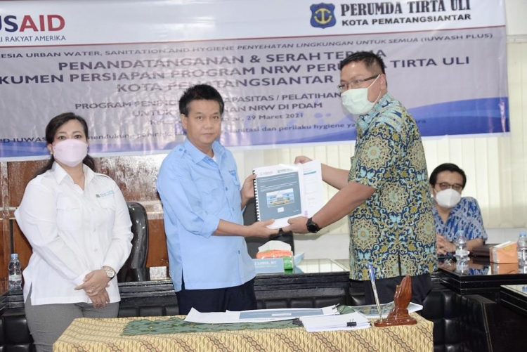 Direktur Utama Perumda Tirtauli Ir Zulkifli Lubis MT didampingi Direktur Umum Perumda Tirtauli Berliana Napitu menyerahkan Dokumen Persiapan Program Non Revenue Water (NRW) dengan IUWASH PLUS.