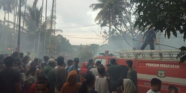 Kerumanan warga tengah menyaksikan upaya pemadaman api kebakaran oleh Damkar Siantar, Jumat (5/3) sore. (isiantar/jw-NM).