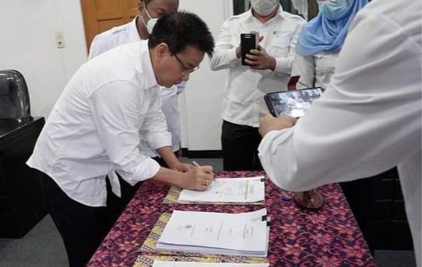 Dirut Perumda Tirtauli Zulkifli Lubis MT, menandatangani dokumen pendukung hibah NRW) program peningkatan kapasitas dan pelatihan penurunan NRW oleh USAID IUWASH PLUS kepada Perumda Tirtauli, Senin (24/8/2021).