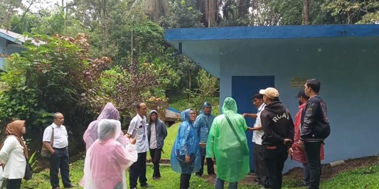Kepala Bagian Produksi Perumda Tirtauli, Dorlim Pasaribu, sedang mengajak jurnalis berkeliling umbul Mual Goit sembari menjelaskan cara kerja produksi air minum di umbul tersebut. (isiantar/nda).